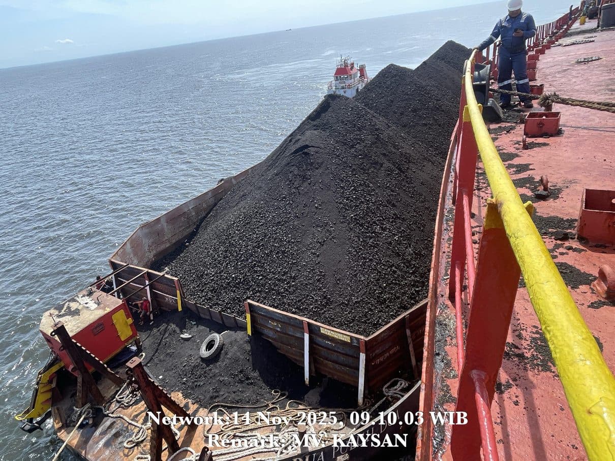 Proses pemuatan batu bara dari tongkang ke kapal induk di area anchorage