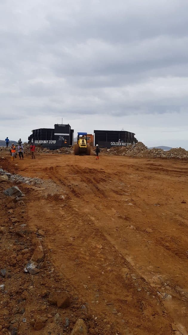 Alat berat menata stockpile komoditas di area pemuatan tepi sungai