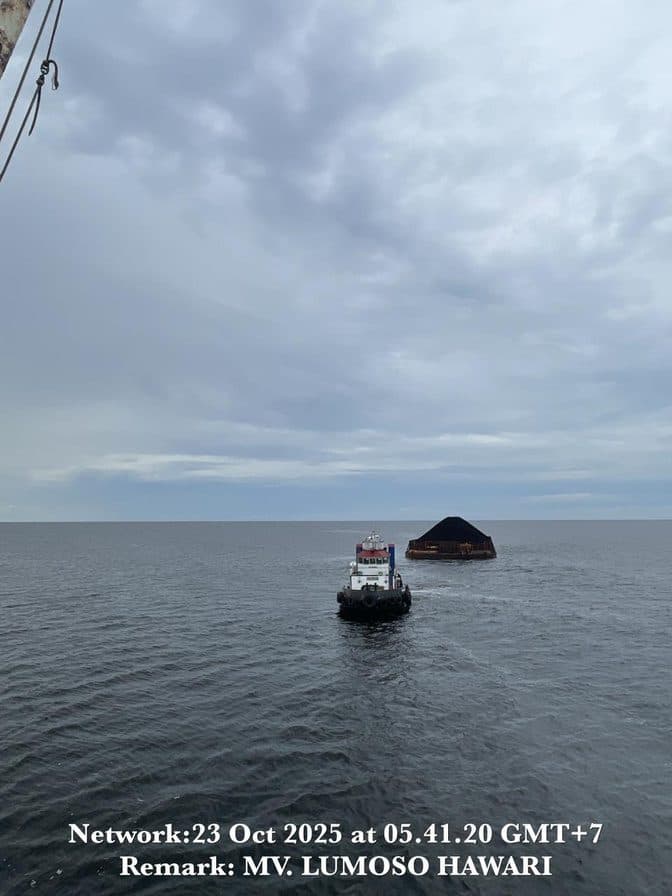 Kapal tunda menarik tongkang melintasi laut lepas dalam pelayaran domestik